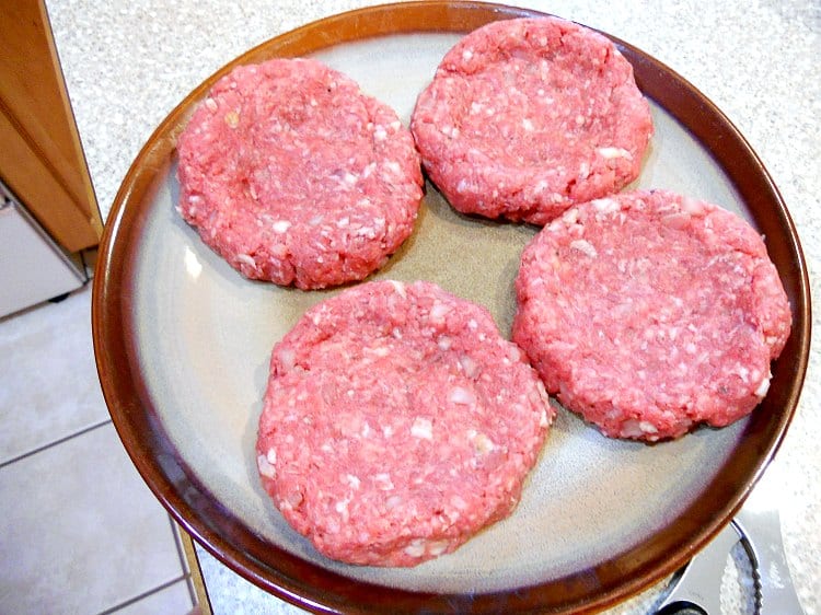 4 uncooked bison burger patties to make copycat big mac on a plate ready to be grilled.