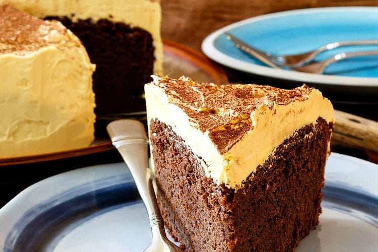 a slice of chocolate stout cake with a thick layer of caramel frosting on a blue plate