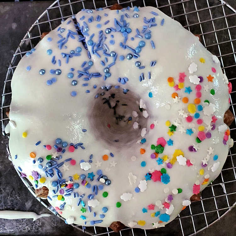 An overhead shot of glazed cake on a cooling rack with different sprinkles on it.
