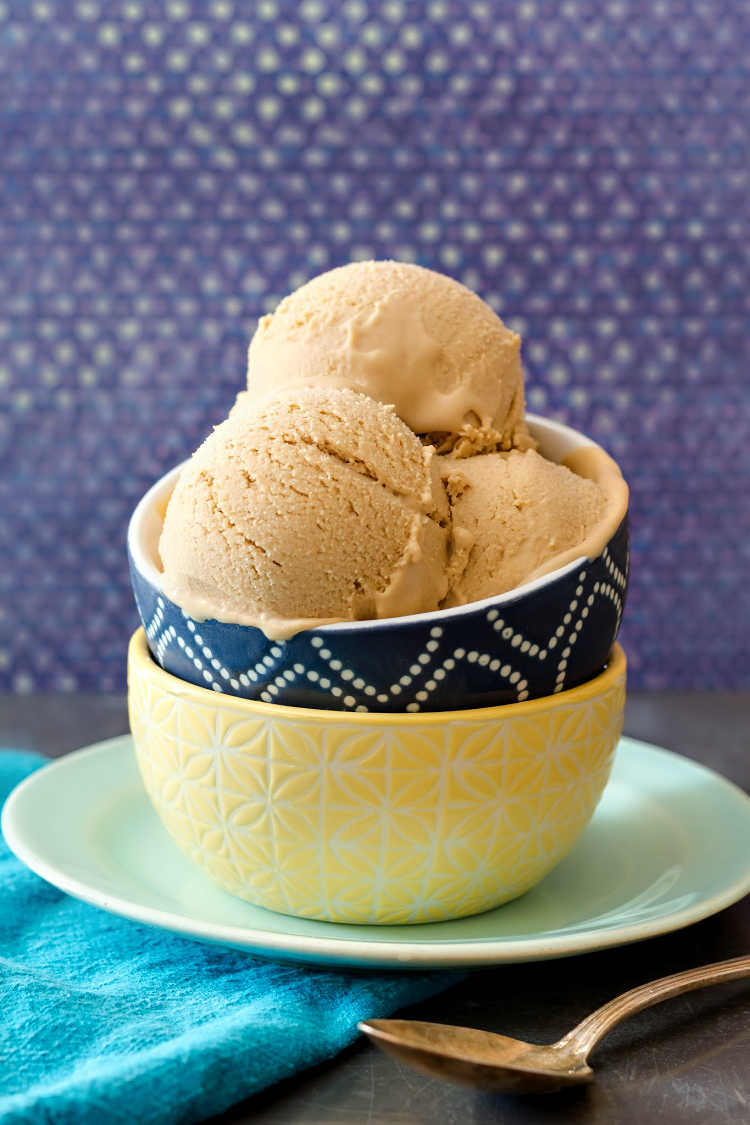 A bowl with 3 scoops of ice cream on a blue plate.