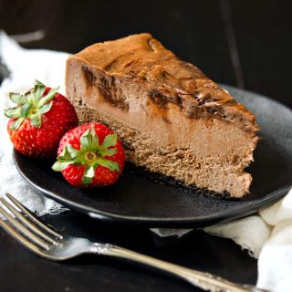 square image of slice of nutella cheesecake on a plate with 2 strawberries