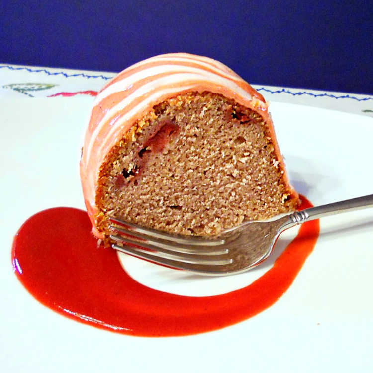 a slice of strawberry moscato pound cake on a white plate with a swoosh of sweetened strawberry puree 