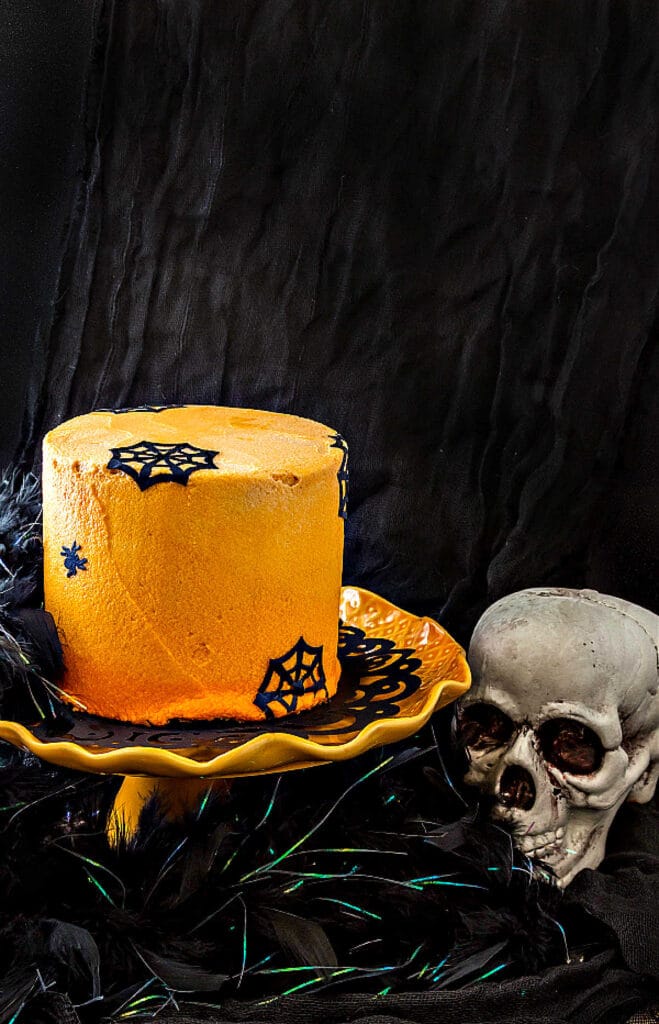 An orange frosted chocolate Halloween cake decorated with edible "paper" spiders and spider webs.