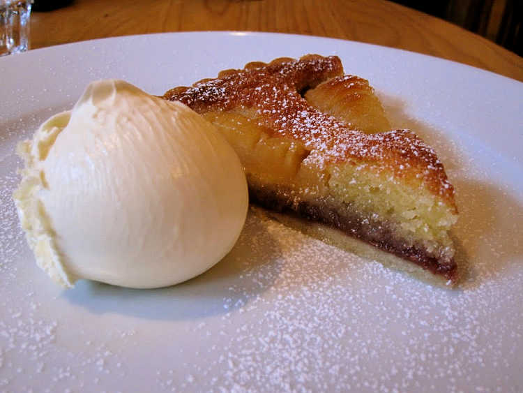 a slice of almond tart with frangipane and a scoop of ice cream on a plate