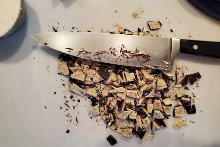 A cutting board with chopped mint bark and a chef's knife.