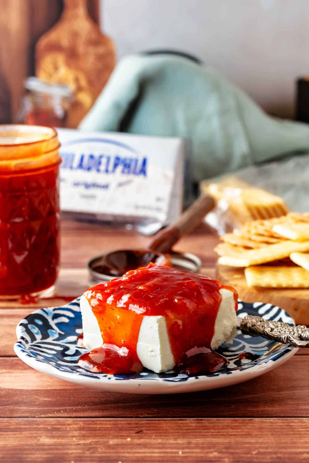 A squre of cream cheese on a plate with red sauce poured over the top of it.