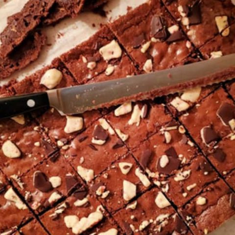 overhead shot of a slab of sliced brownies with a serrated knife