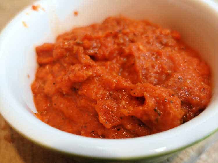 A white ramekin of thick tomato sauce.