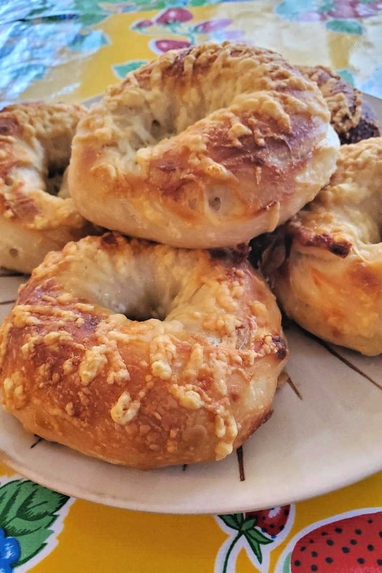 A plate of asiago bagels on a yellow tablecloth.