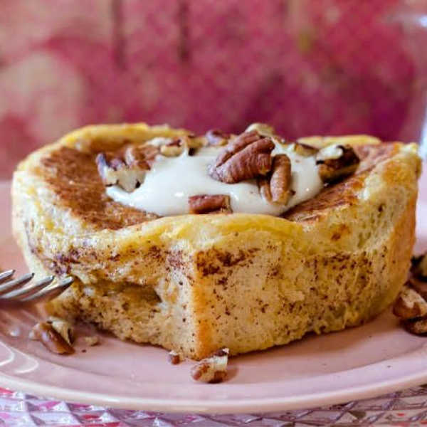 Square image of heart-shaped stuffed French toast on a pin plate with cream and chopped pecans.