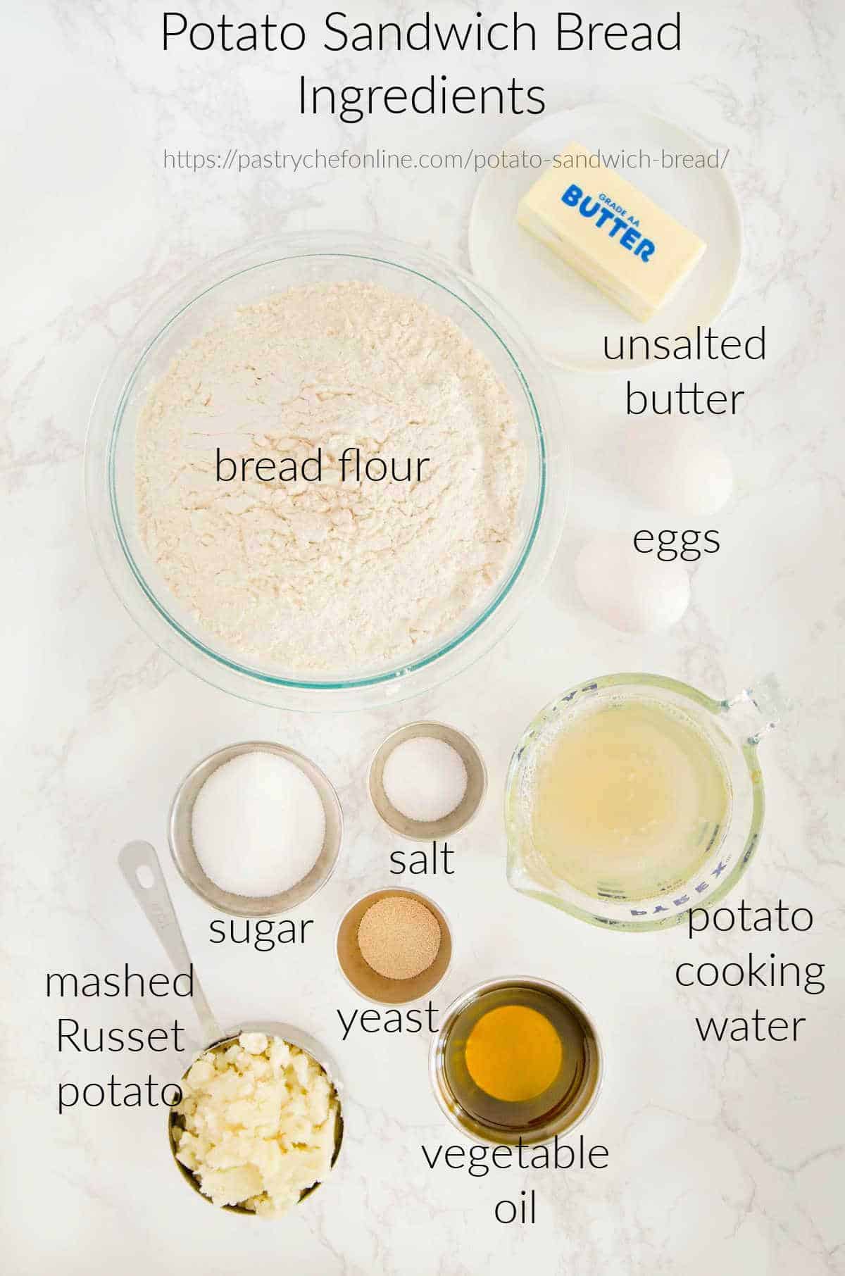 An overhead view of all the ingredients needed to make potato bread: butter, bread flour, eggs, sugar, salt, Russet potato, potato cooking water, yeast, and vegetable oil.