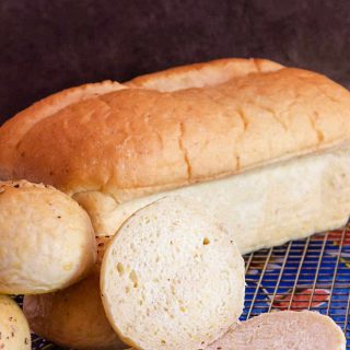 loaf of grits bread with a cut roll on a cooling rack