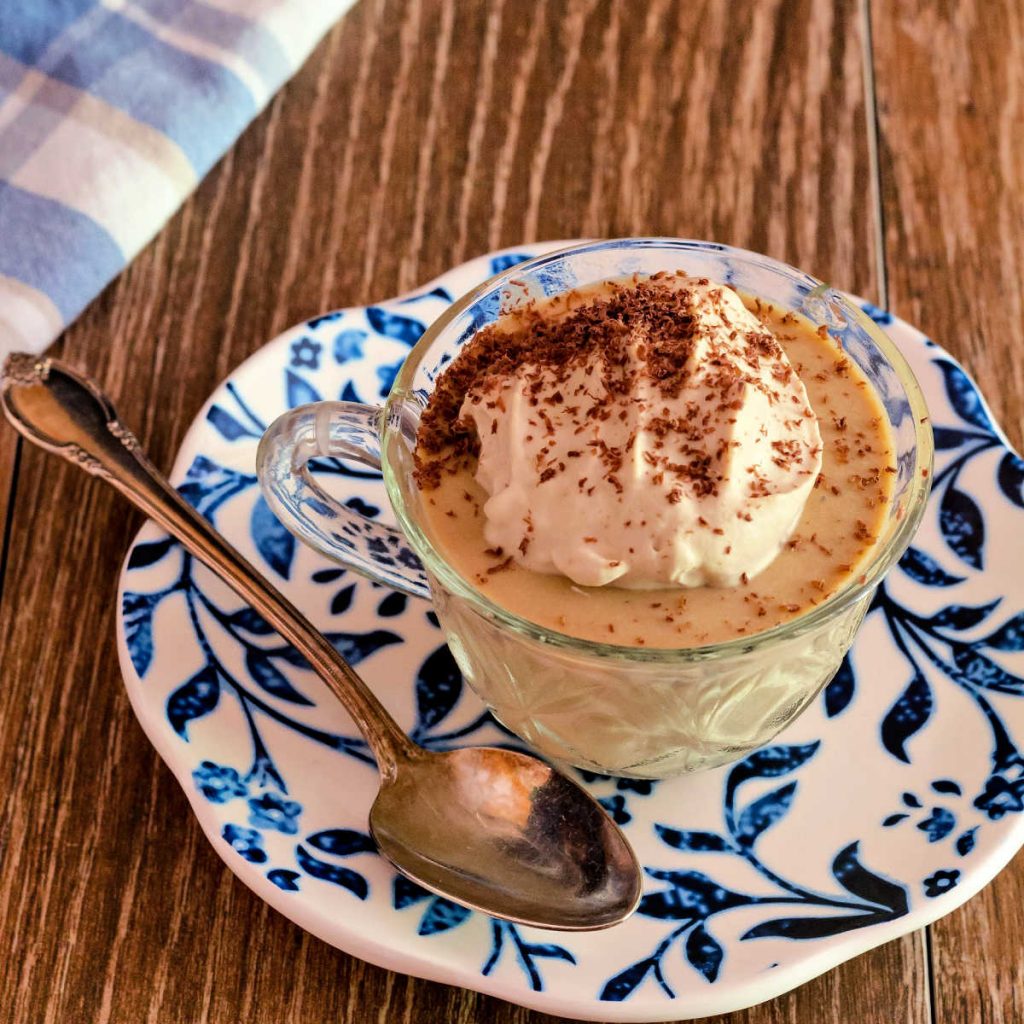 glass coffee cup of coffee panna cotta on a blue patterned plate