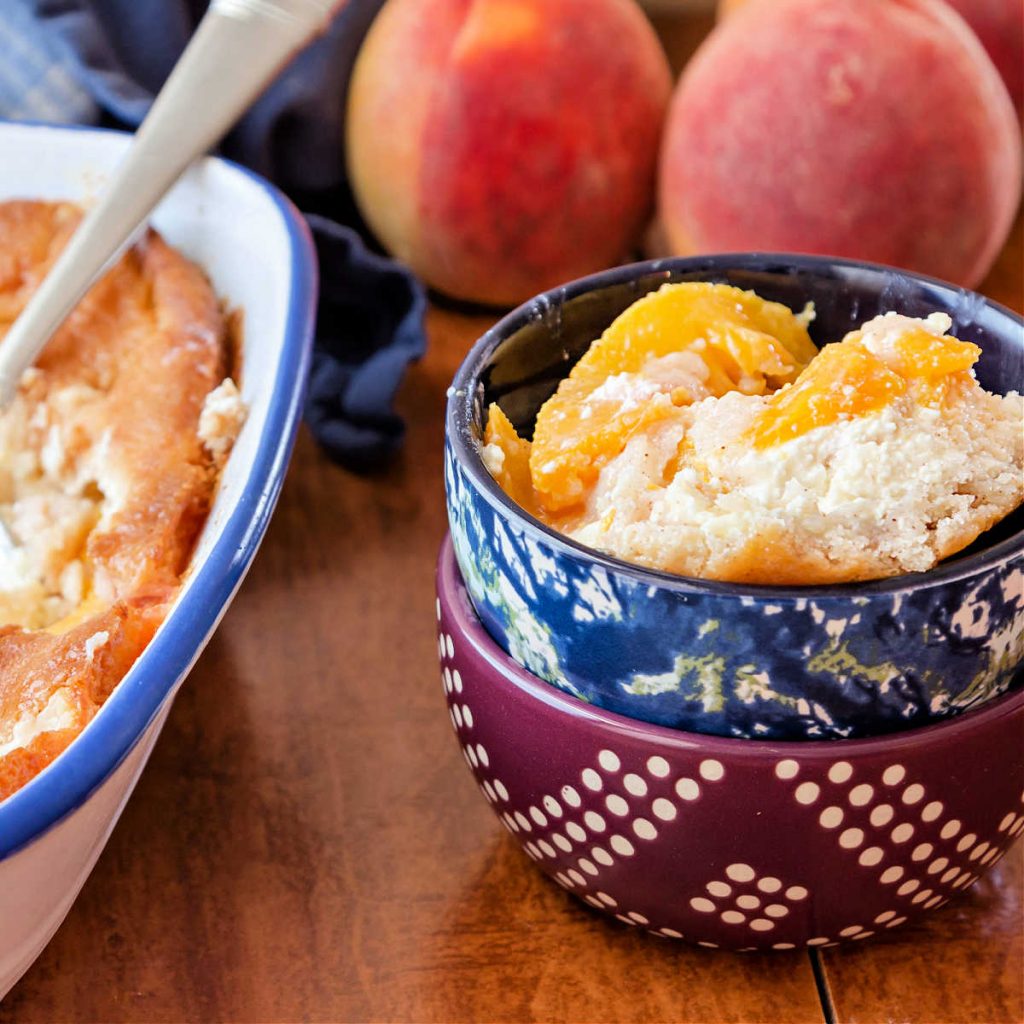 A  bowl of peaches and cream cobbler with next to baking dish with peach cobbler in it.