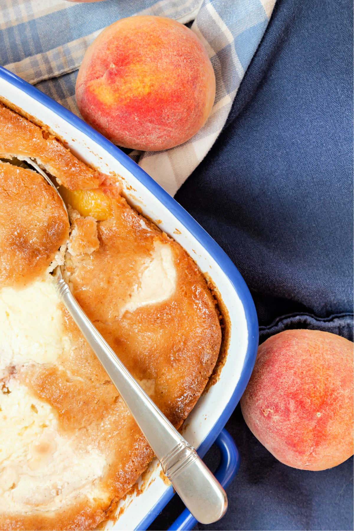 An overhead view of baking dish of peach cobbler and 2 peaches.