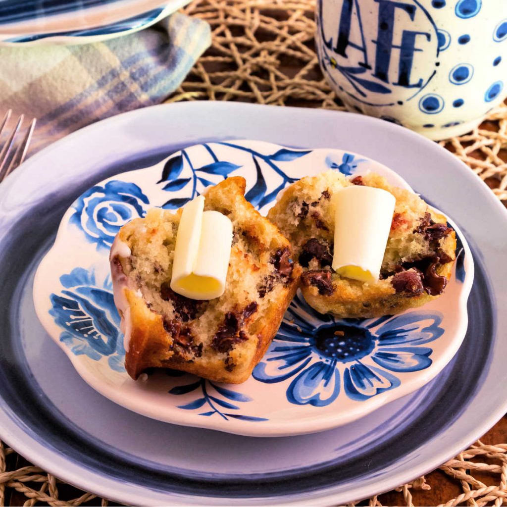 A split buttermilk muffin with cherries, chocolate, and pecans served with curls of butter.