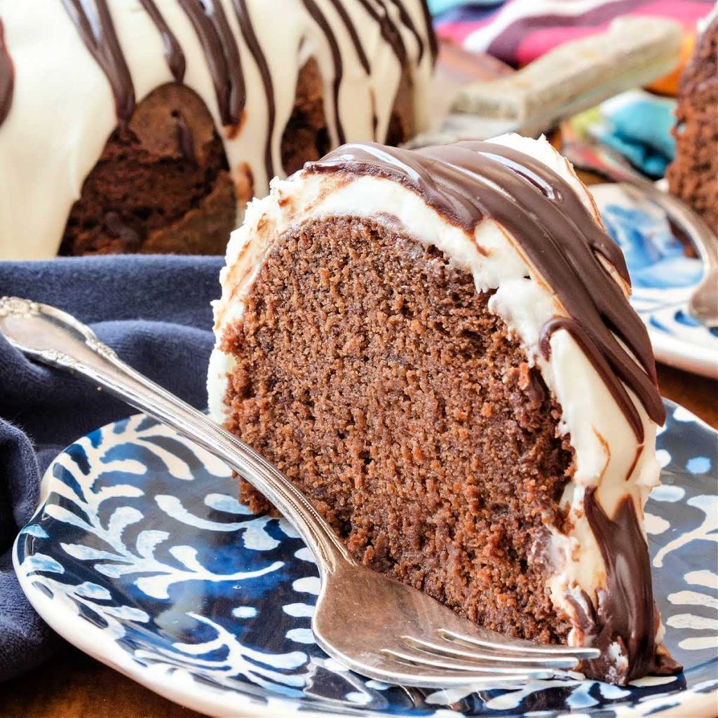 A slice of glazed chocolate pound cake with a fork on a blue plate.