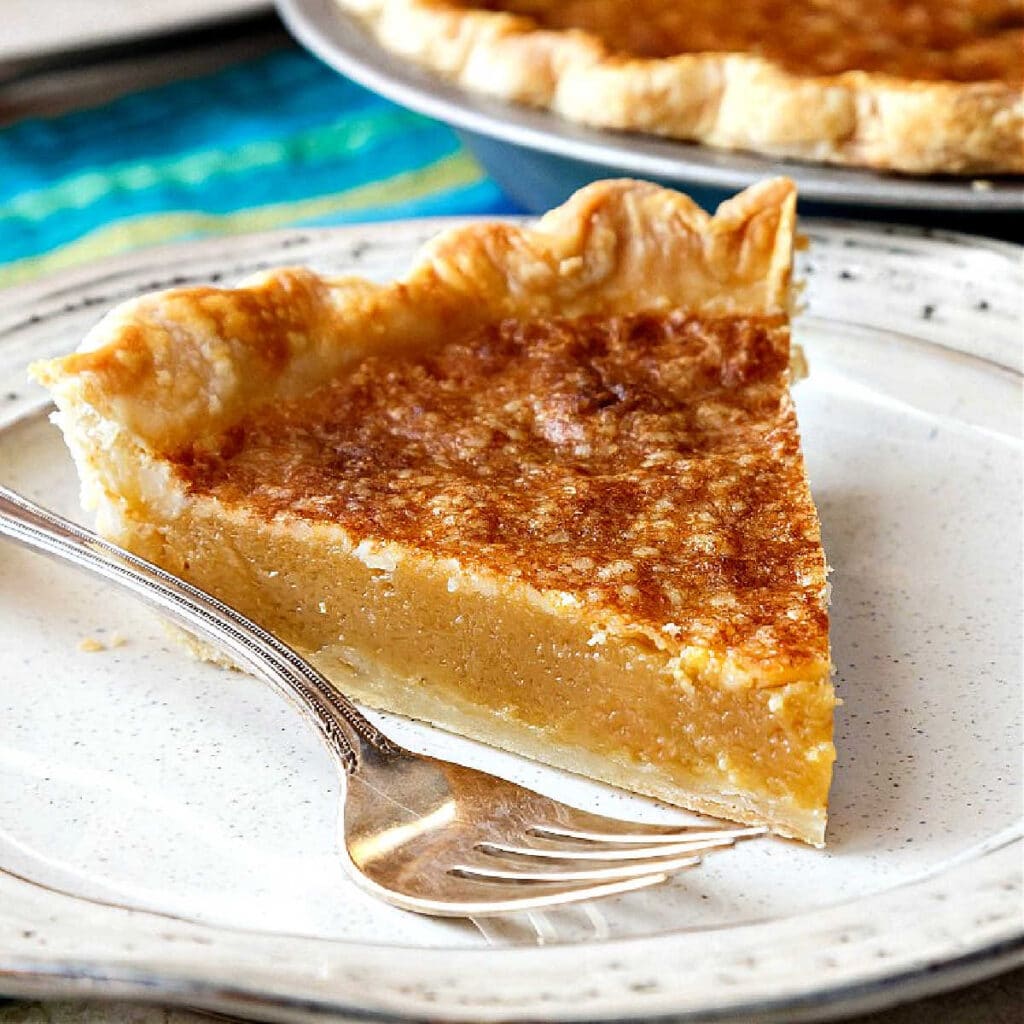 A slice of vinegar pie on a beige-speckled plate with a fork.