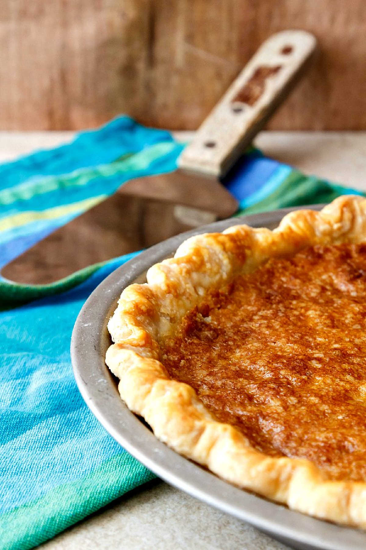 A partial shot of a whole vinegar pie in a metal pie tin.