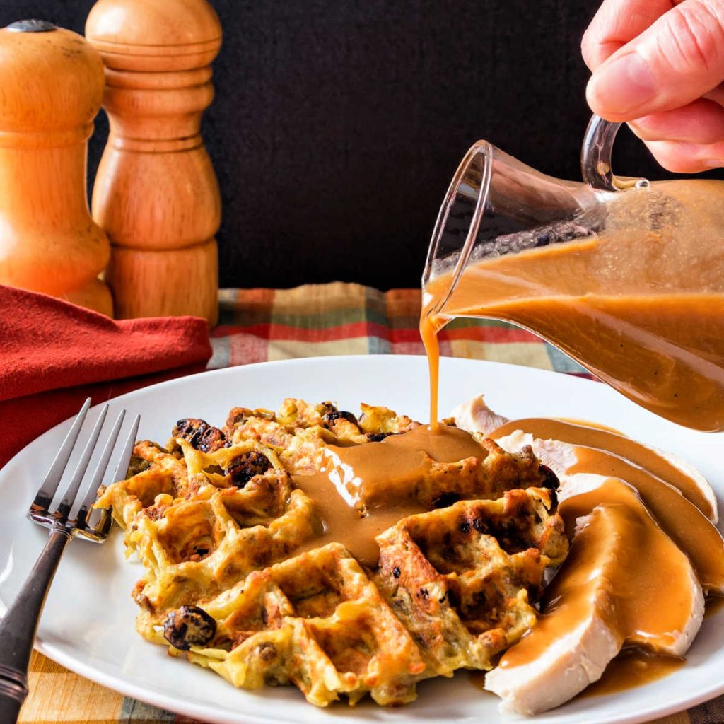 Gravy covered potato stuffing waffle on a plate with turkey.