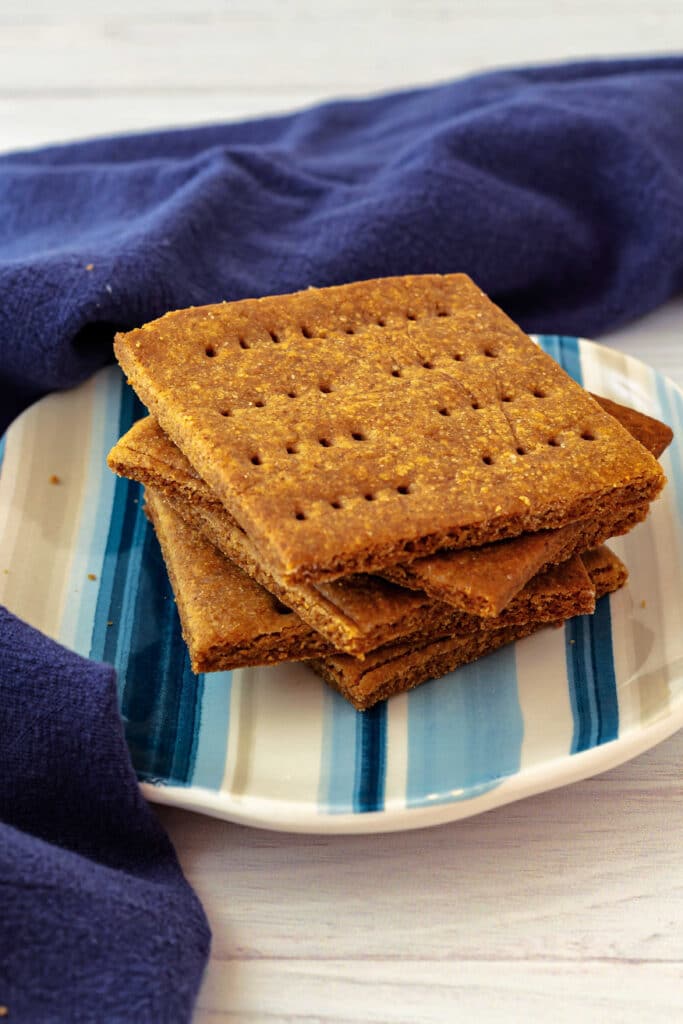 A stack of cinnamon Graham crackers on a blue striped plate.