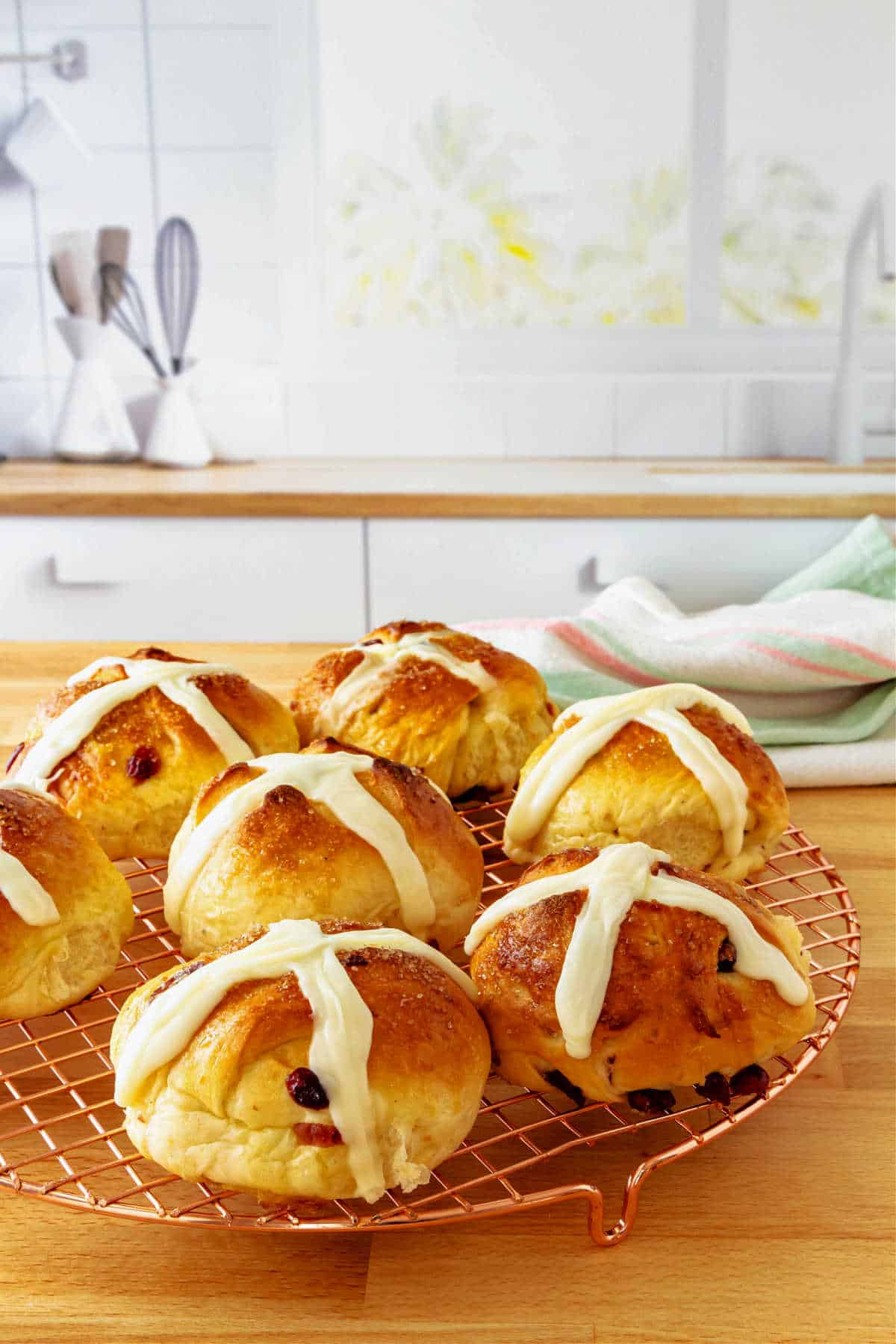 A cooling rack with cream cheese hot cross buns on it.