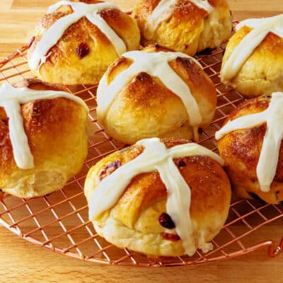 A square image of hot cross buns on a cooling rack.