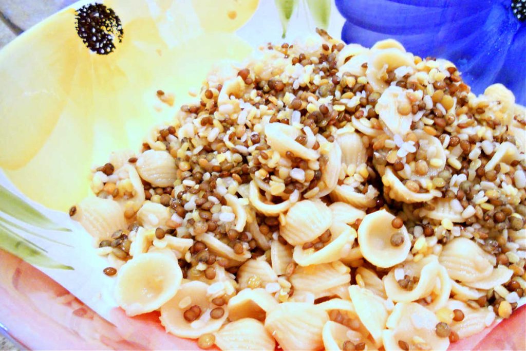 A bowl with cooked orecchiette pasta and lentils.