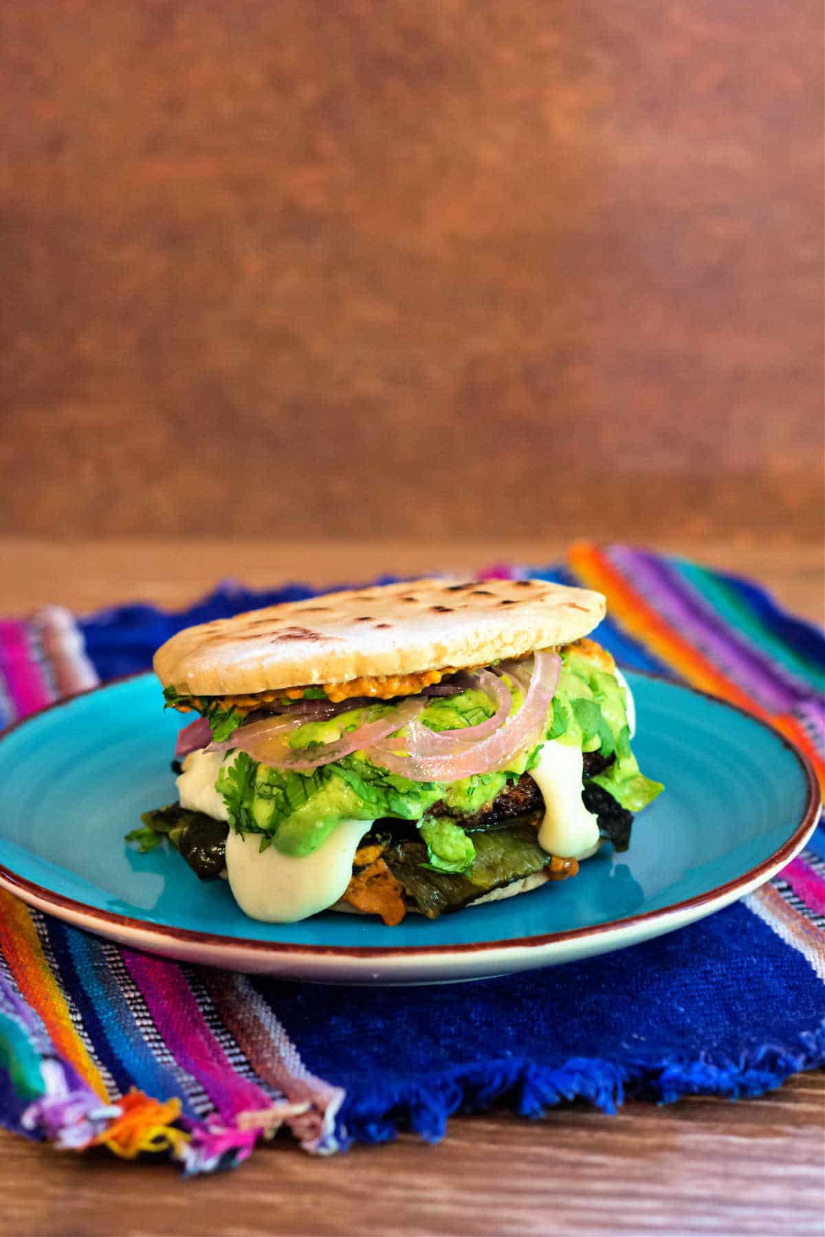 A burger with stuffed gorditas for buns on a blue plate
