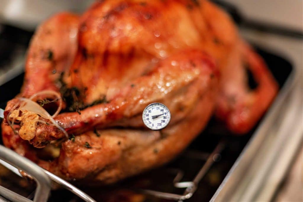 A turkey with a meat thermometer inserted into the thigh.