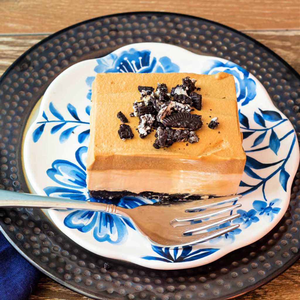 A high-angle shot of a square of no bake coffee cheesecake on a blue flowered plate with a fork.