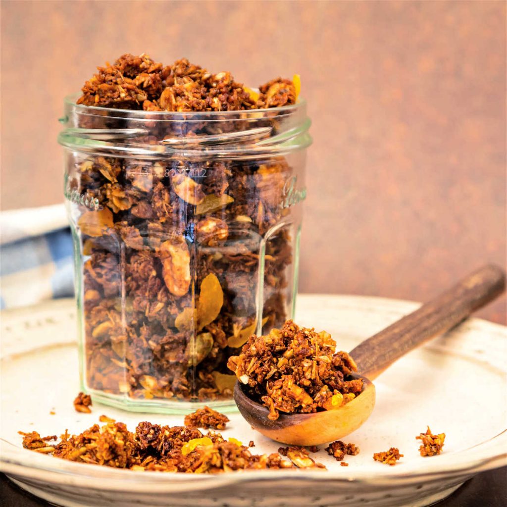 A square image of a glass jar filled with homemade granola.