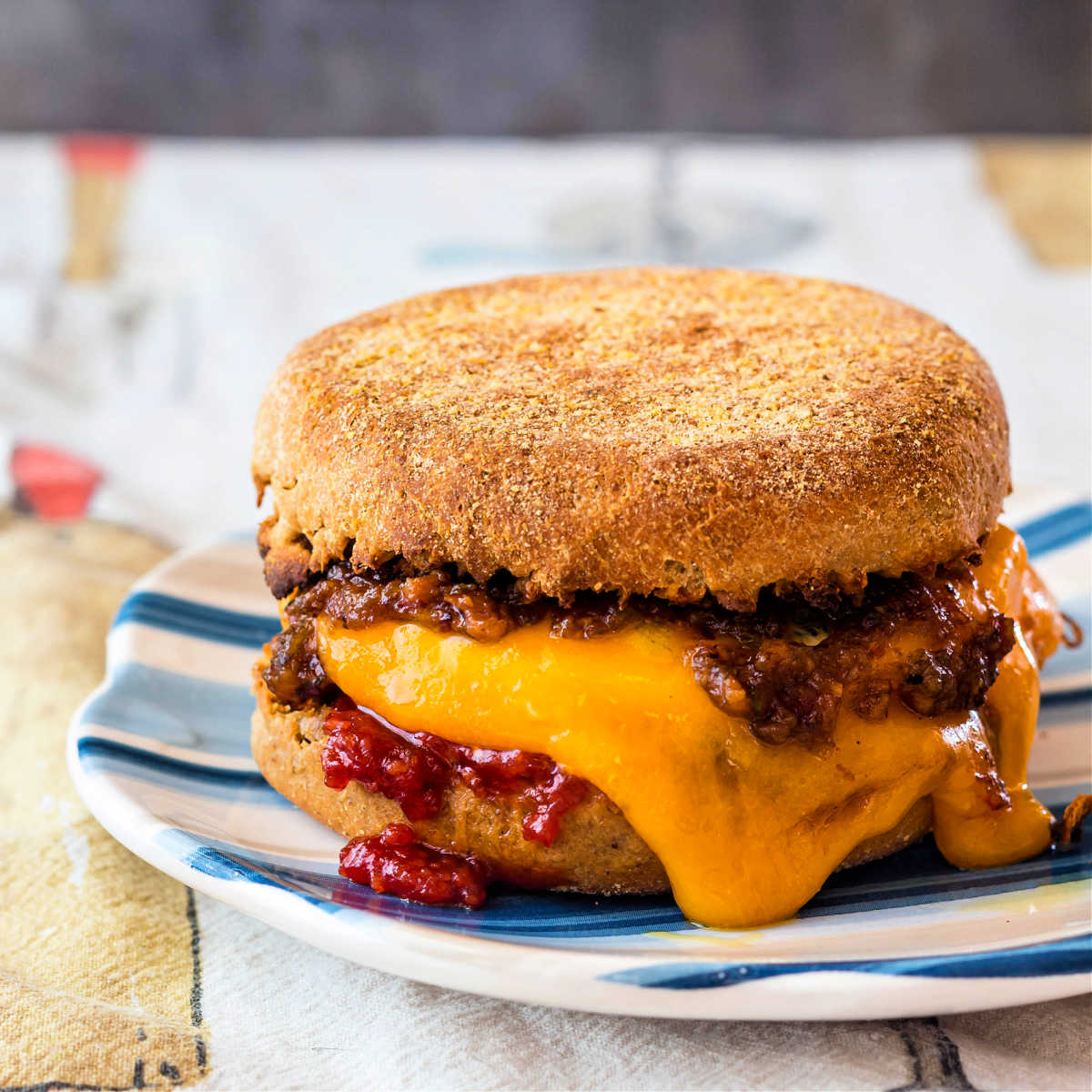 A close up of a breakfast sandwich with melting cheese dripping down the sides.