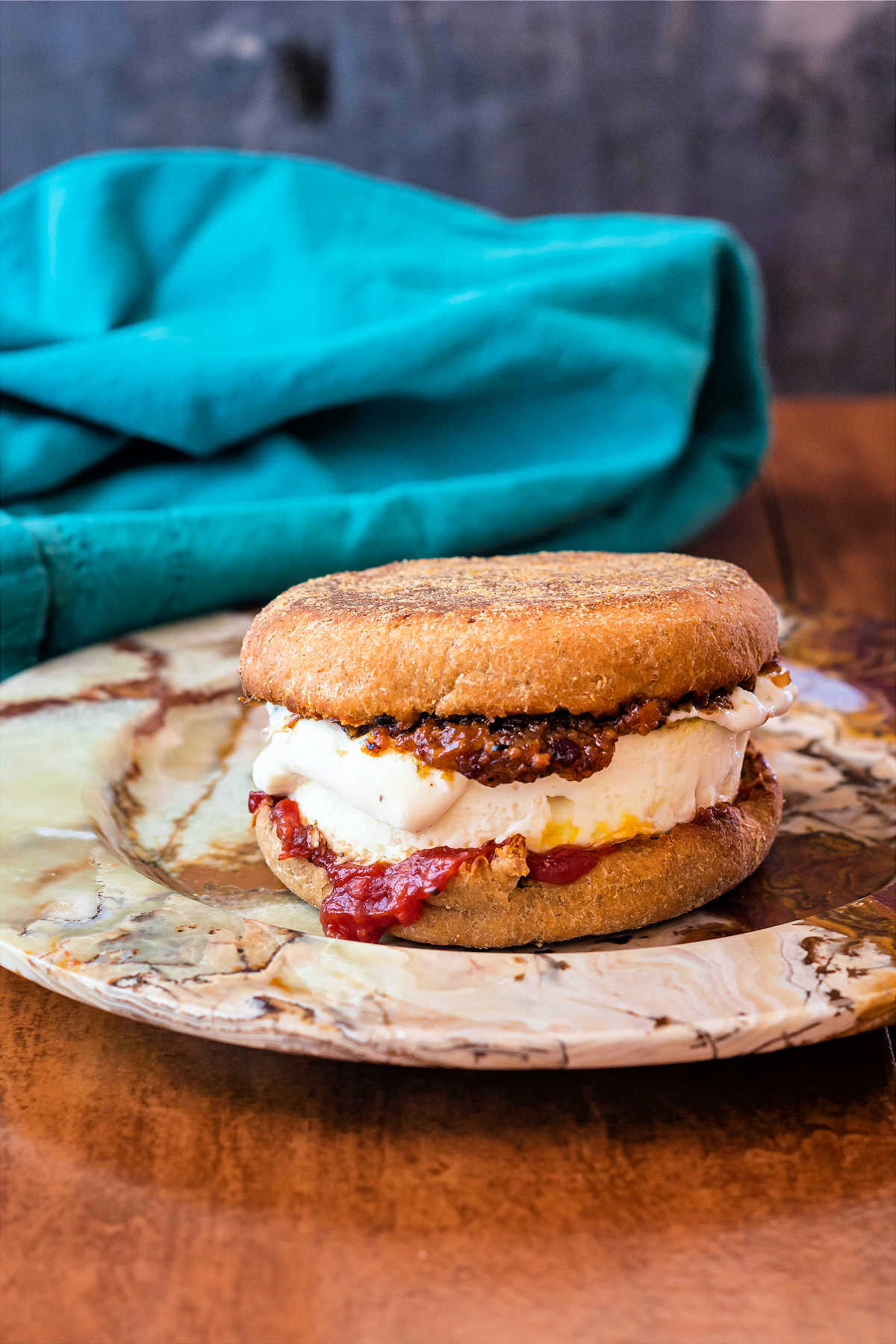 A spent grain English muffin egg sandwich on a neutral-colored plate.