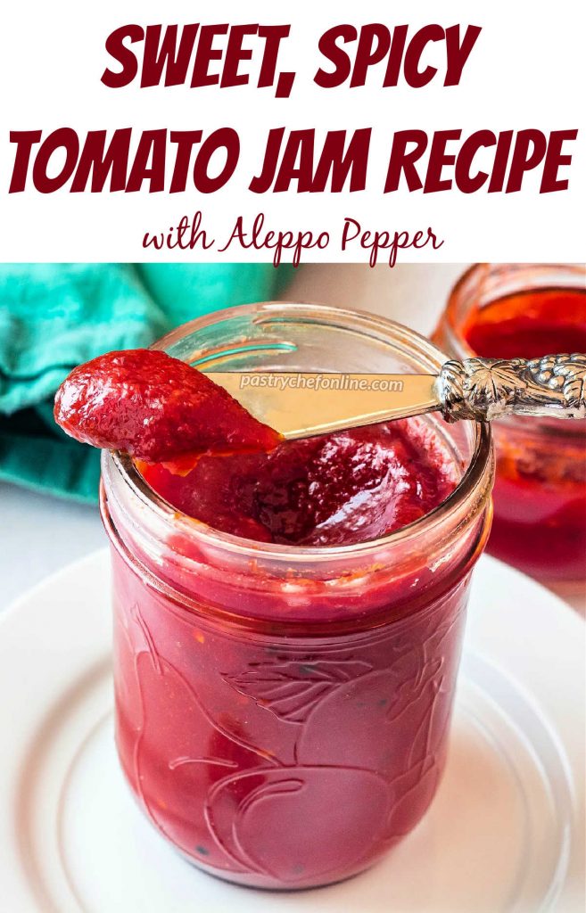 A jar of jam with a silver spreader balanced on the rim with jam on it. Text reads, "sweet, spicy tomato jam recipe. With Aleppo pepper."