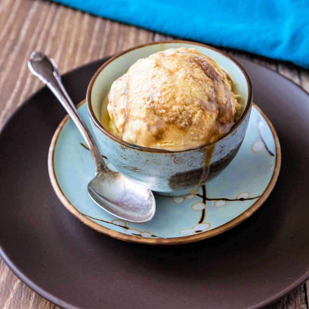 3/4 shot of a dish of butterscotch ripple ice cream with a spoon.
