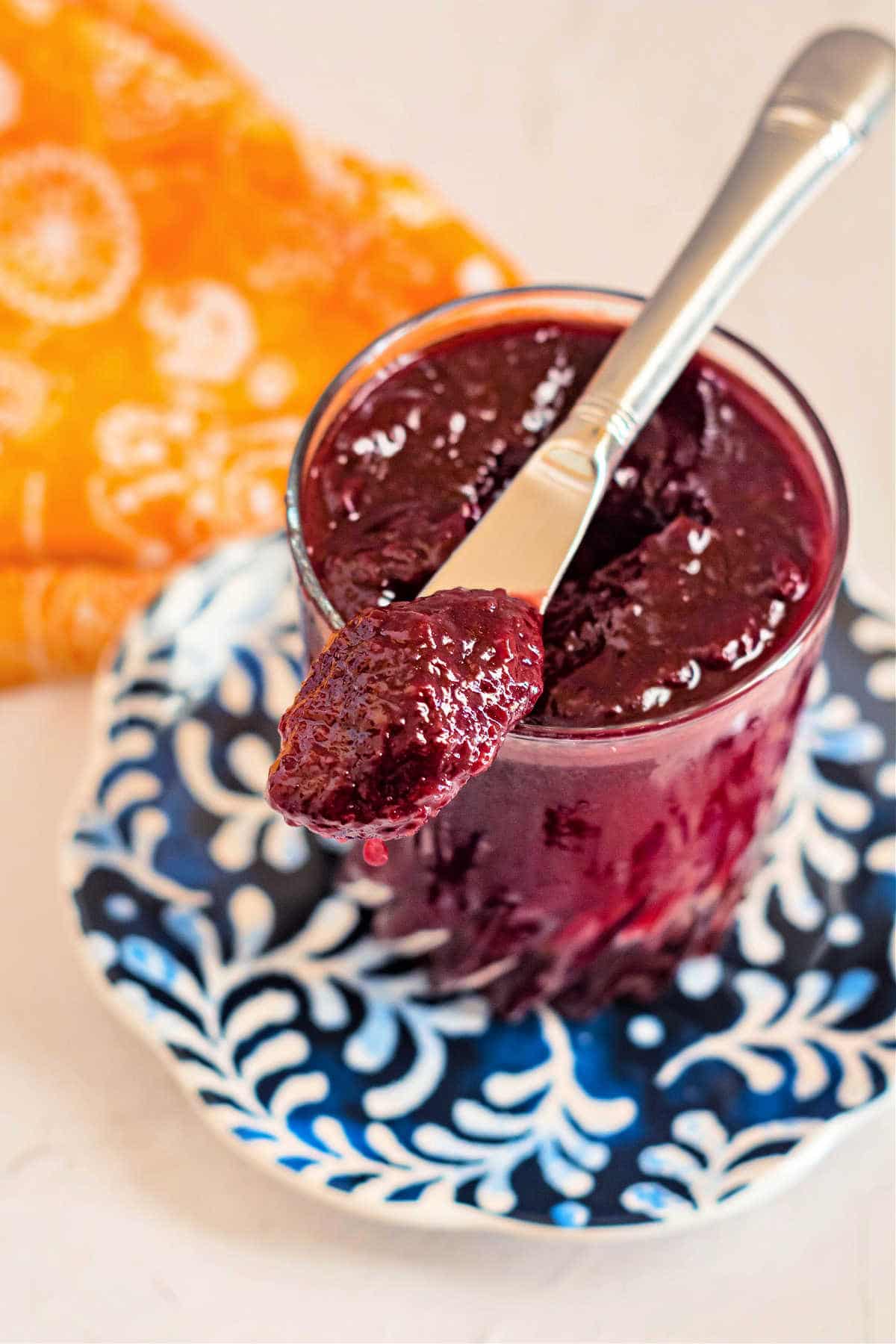 A jar of plum jam with a knife in it.