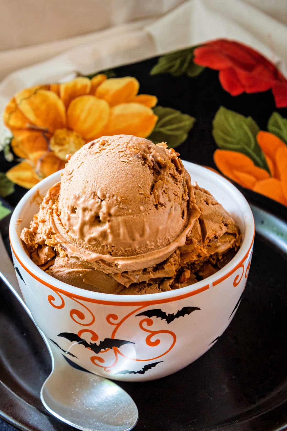 A white dish decorated with orange swirls and black bats filled with scoops of ice cream.