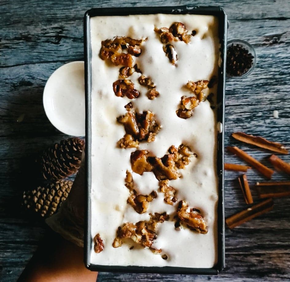 An overhead shot of a rectangular container of ice cream with candied pecans on top.