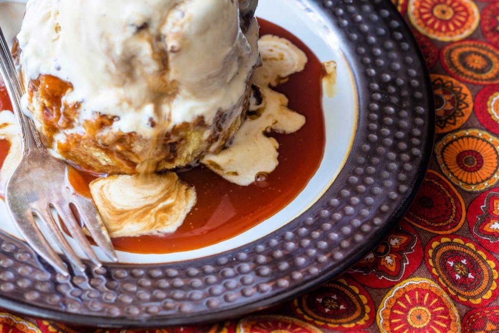 A close up of apple cider caramel sauce on a plate with swirls of caramel ice cream melting into it.