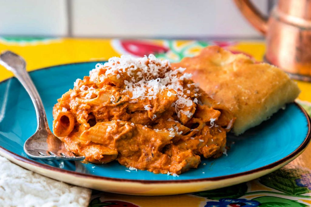 Pasta in sauce and focaccia on a blue plate.