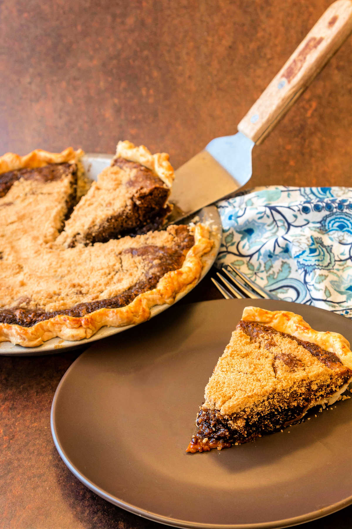 A slice of molasses pie and the whole pie behind it.