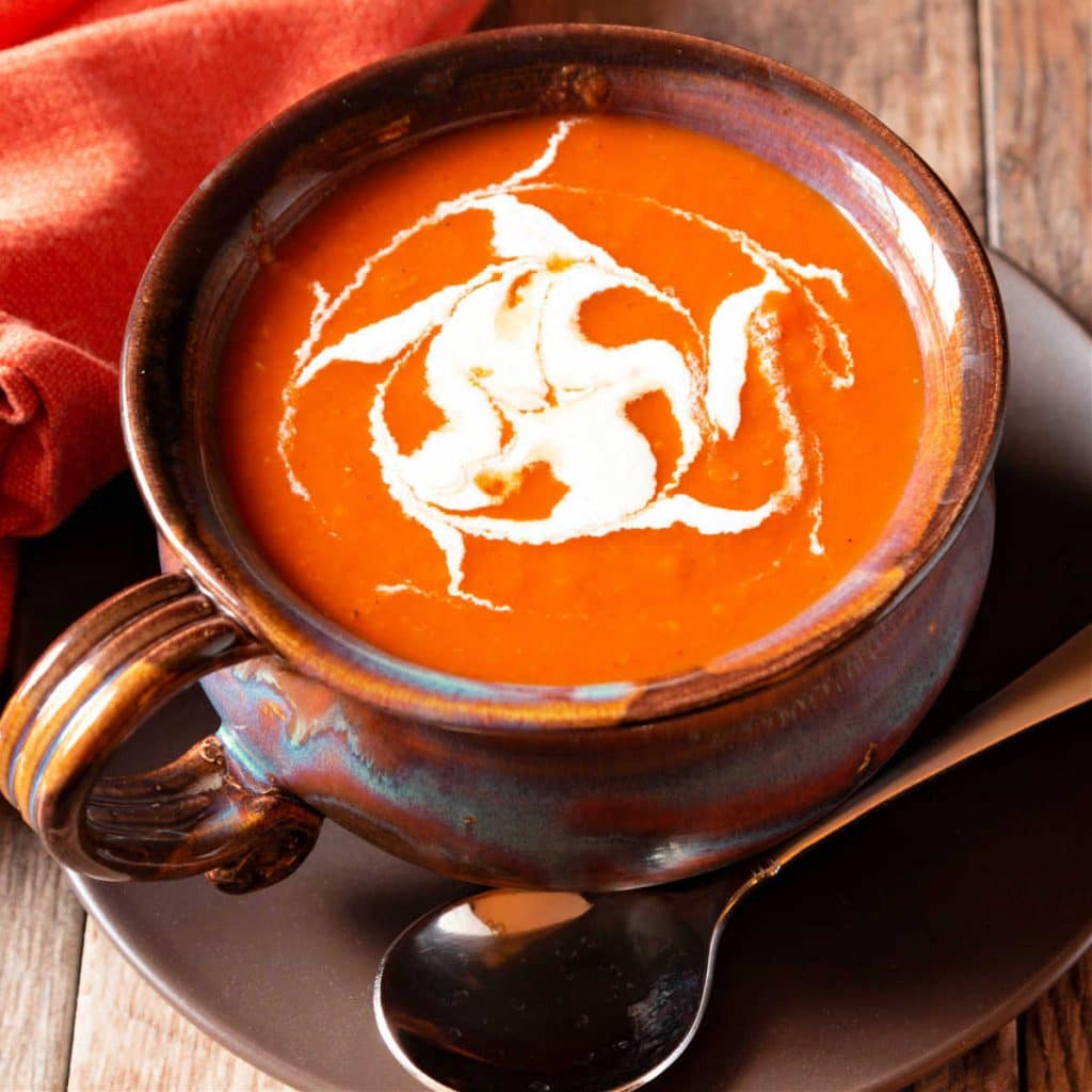 A bowl of cajun tomato soup with spiced cream swirled on top.