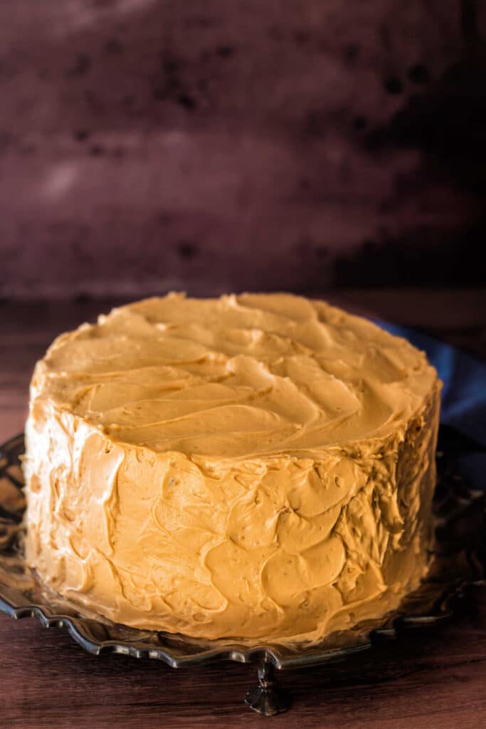 A whole layer cake frosted with caramel frosting. The cake is frosted with visible knife marks and "swoops" rather than smooth.
