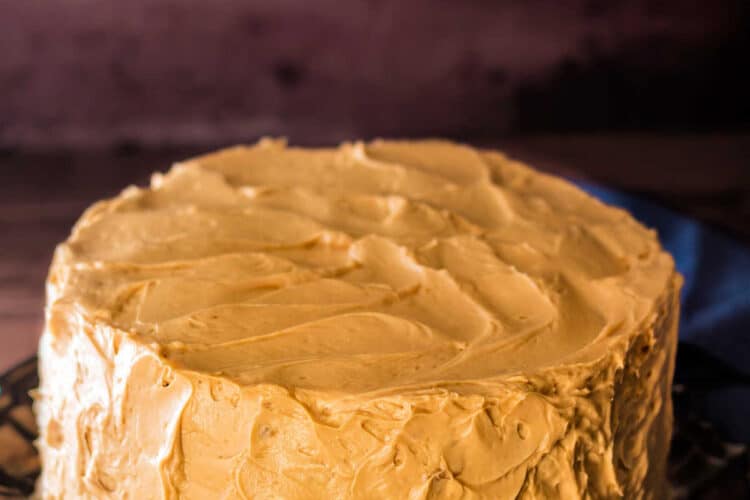 A whole layer cake frosted with caramel frosting. The cake is frosted with visible knife marks and "swoops" rather than smooth.