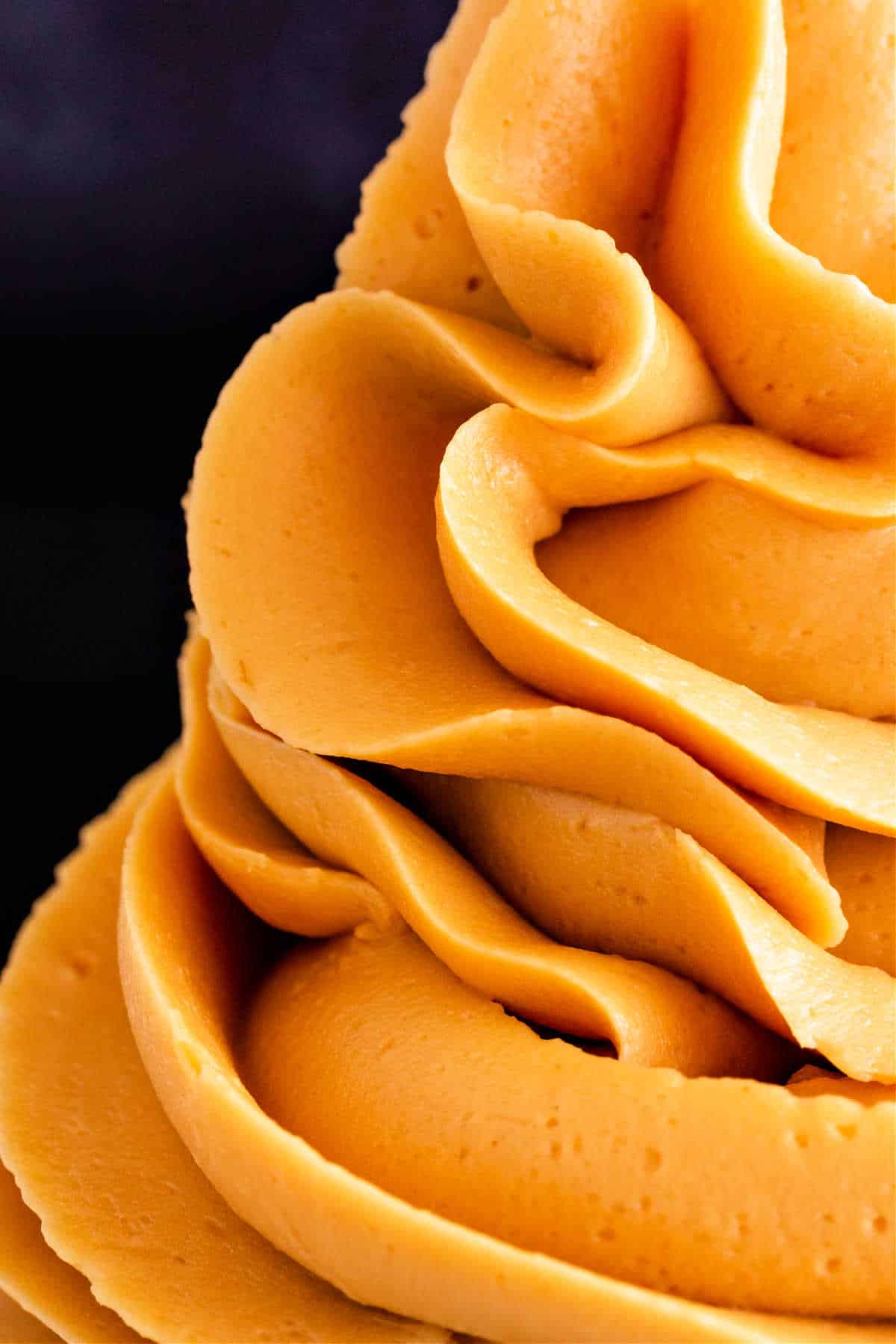 An extreme close-up of piped caramel frosting showing the smooth and fluffy texture.