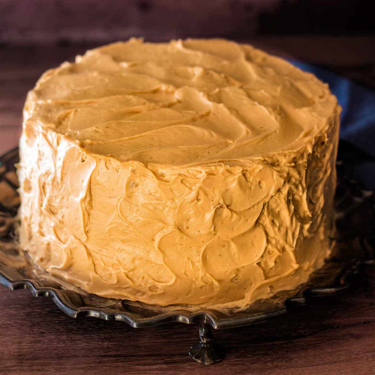 Close up of a whole cake covered in fluffy caramel frosting.