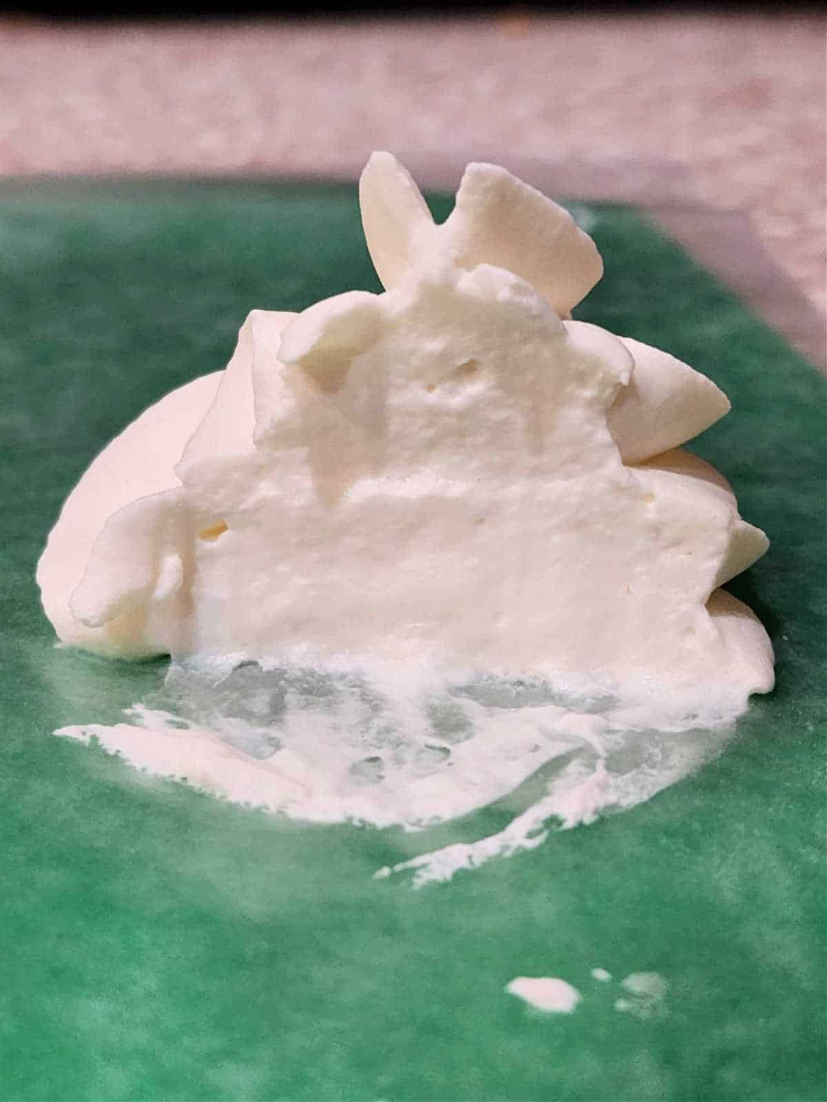 Piped whipped cream sliced in two to show the inside texture: smooth and creamy.