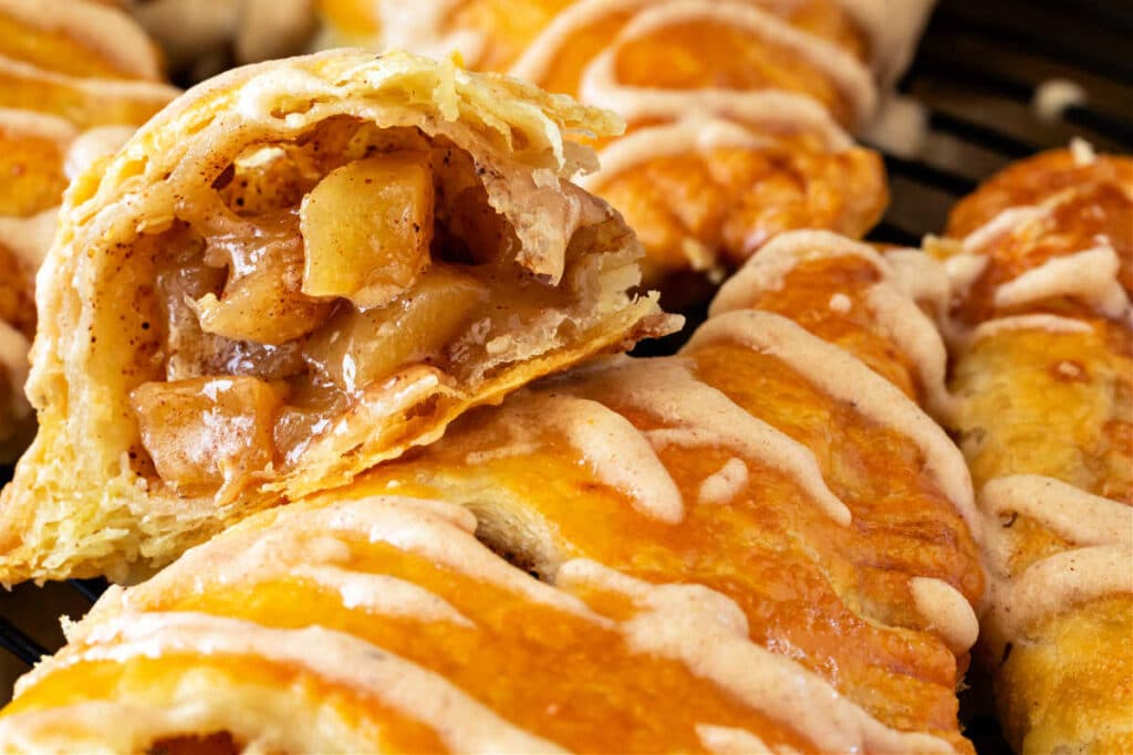 A cut-open apple turnover showing the diced apple filling inside flaky puff pastry.