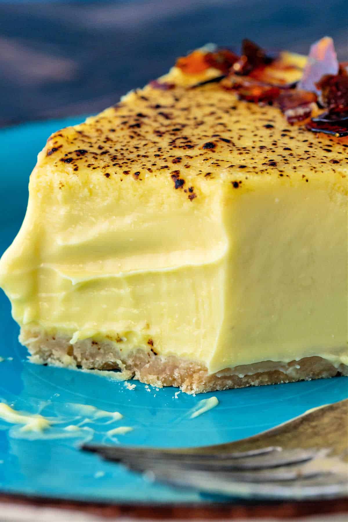 A close up of a slice of pale yellow cheesecake with a bite cut out of it. 